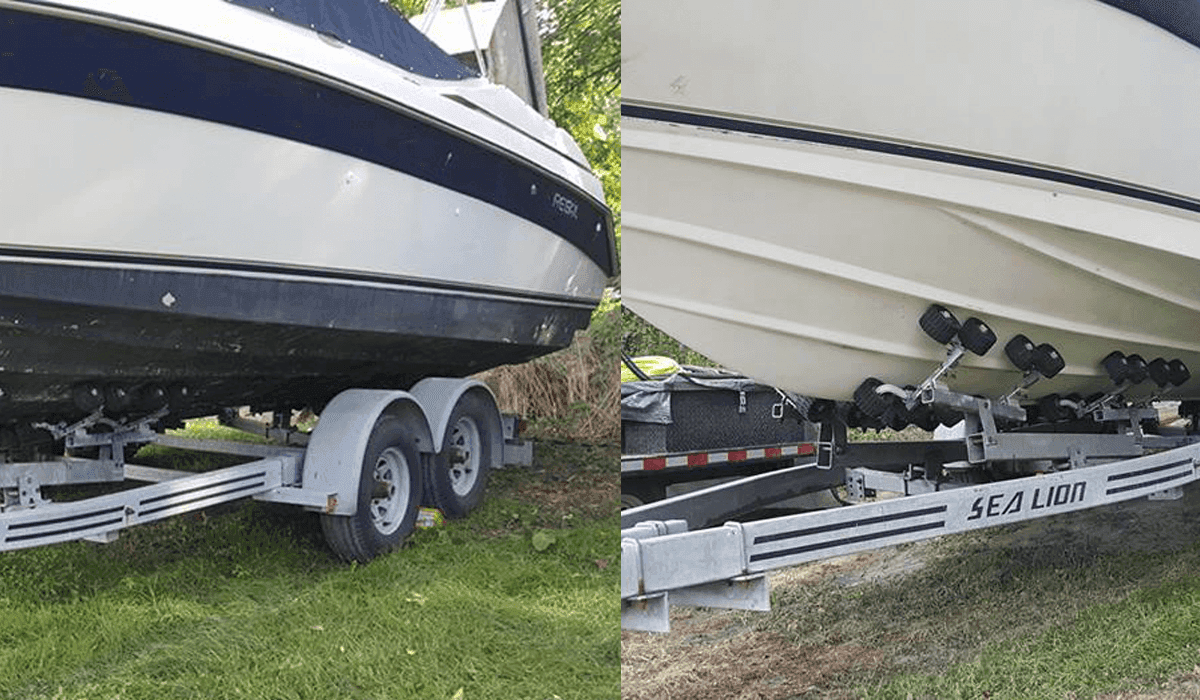 A boat is sitting on a trailer in the grass